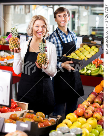 Senior woman and young man offering seasonal fruits Senior woman and young man offering seasonal fruits 24267287