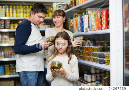Happy young parents with little girl buying tinned Happy young parents with little girl buying tinned 24267289