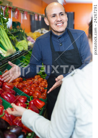 Young woman buying seasonal vegetables in grocery from mature seller Young woman buying seasonal vegetables in grocery from mature seller 24267291