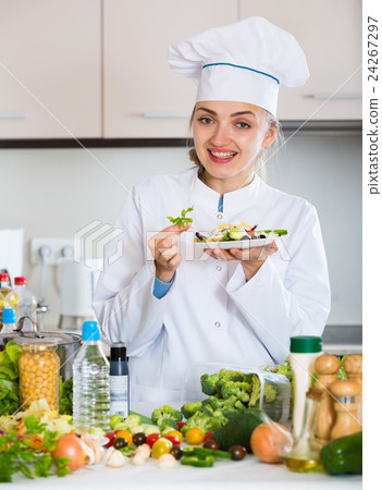Positive chef decorating salad with parsley in kitchen 24267297