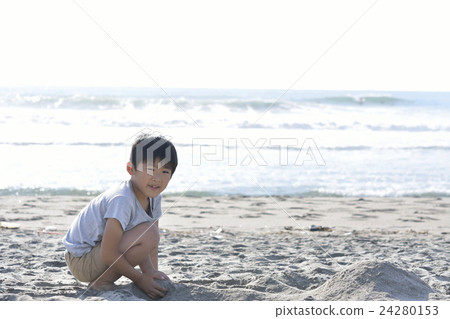 A boy making a sandy mountain on a sandy beach A boy making a sandy mountain on a sandy beach 24280153