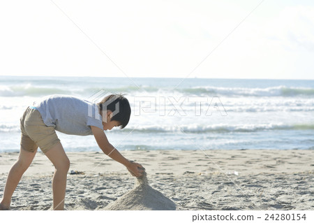 A boy making a sandy mountain on a sandy beach A boy making a sandy mountain on a sandy beach 24280154