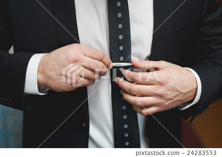 Man in black suit putting on tie clip 24283553