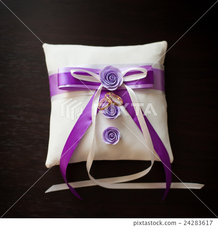 Golden wedding rings on decorated little pillow 24283617