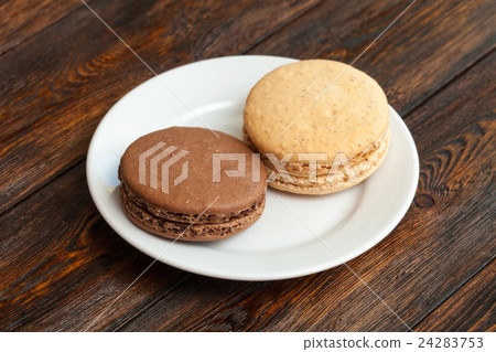 Two traditional french chocolate macarons on plate 24283753