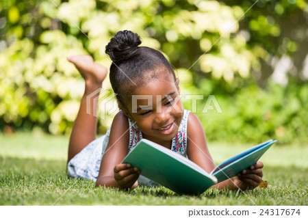 Little girl reading a book at park Little girl reading a book at park 24317674