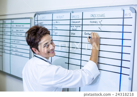 Woman vet from the back smiling and writing something on a board Woman vet from the back smiling and writing something on a board 24318218