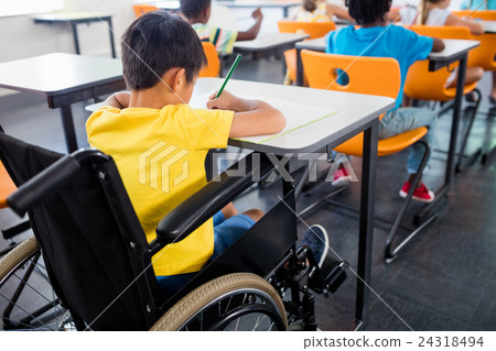 A pupil in wheel chair working at his desk A pupil in wheel chair working at his desk 24318494