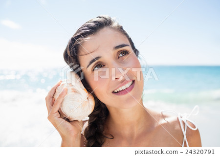 Portrait of smiling woman listening shellfish 24320791