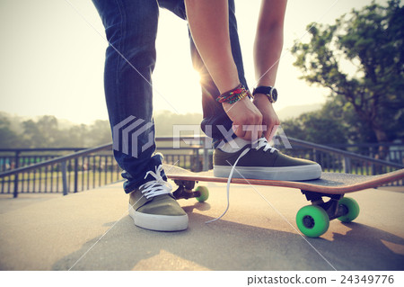 skateboarder tying shoelace at skatepark ramp.. 24349776