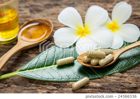 Herbal capsule on wooden spoon with Plumeria flowe 24366336