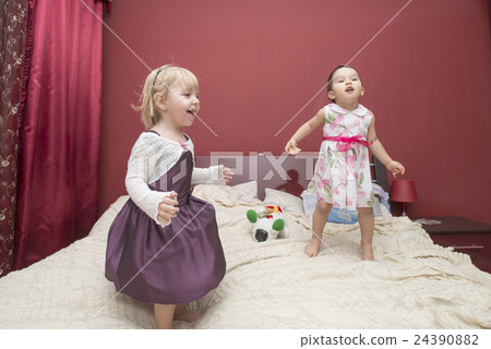 little girls jumping on a bed 24390882