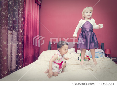 two little girls jumping on a bed 24390883