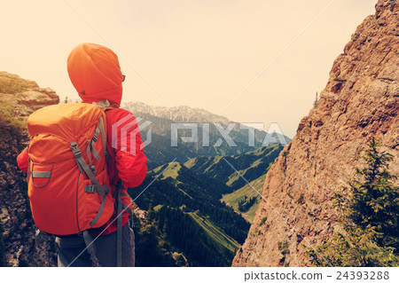 woman backpacker hiking on mountain peak cliff 24393288