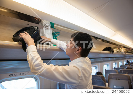 A man putting baggage in the train of a bullet train 24400092