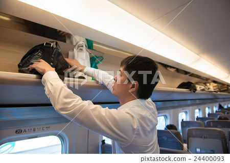 A man putting baggage in the train of a bullet train 24400093