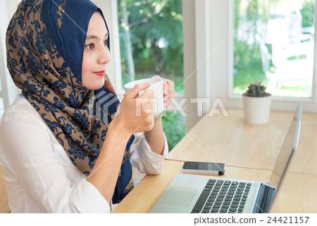 Muslim female with computer on table. Muslim female with computer on table. 24421157