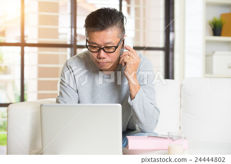 matured asian male using phone and laptop 24444802