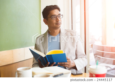 indian casual male reading book and enjoying coffee indian casual male reading book and enjoying coffee 24445117