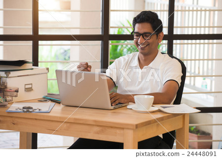 young indian man celebrating success while working young indian man celebrating success while working 24448091
