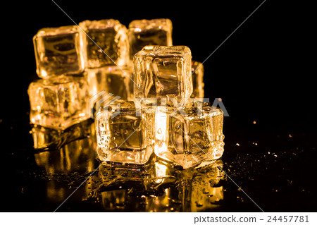 Ice cubes of gold color on a reflective surface. Ice cubes of gold color on a reflective surface. 24457781