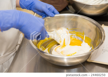 The hand of the pastry making mousse The hand of the pastry making mousse 24460250