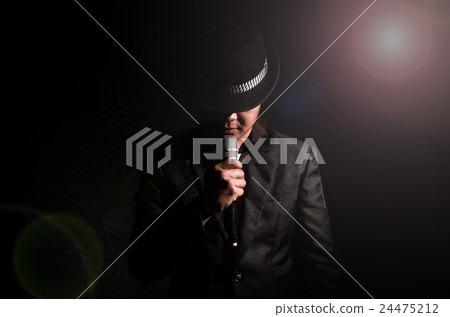 Songer hand holding the microphone and singing on black background with lens flare from spot light, musical concept 24475212