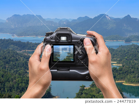 Hands holding the camera which taking photo of Mountain landscape from View point at Khaosok National Park, Ratchaprapha Dam, Thailand Hands holding the camera which taking photo of Mountain landscape from View point at Khaosok National Park, Ratchaprapha Dam, Thailand 24477819