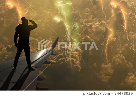 silhouette of man who looking the thunder lightnings over the clouds and storm on airplane wing, Challenge business concept 24478029