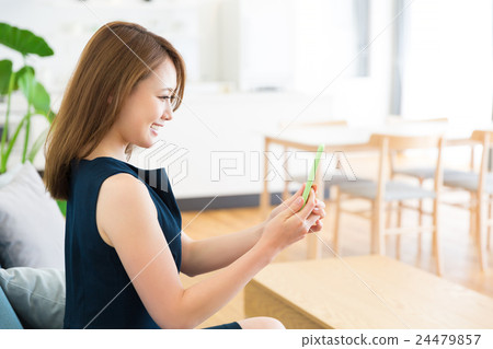 看智能手機的婦女在屋子裡 看智能手機的婦女在屋子裡 24479857