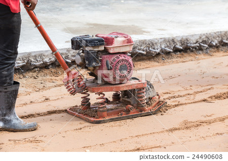 Worker with red soil compactors in construction site 24490608
