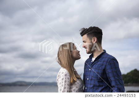 Young couple walking along pebble beach. 24493153