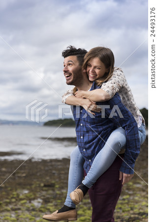 Young couple walking along pebble beach. 24493176