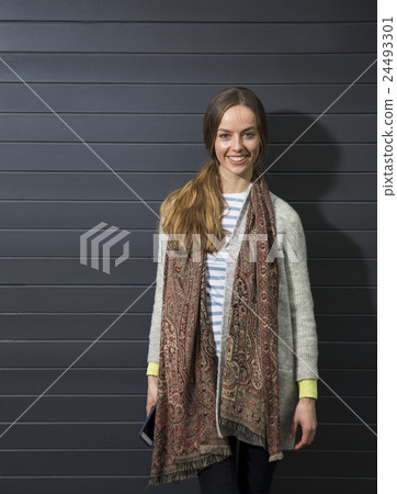 Happy woman leaning against a black wall. Happy woman leaning against a black wall. 24493301
