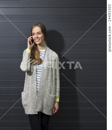 Happy woman using her smartphone and leaning on wall. Happy woman using her smartphone and leaning on wall. 24493303