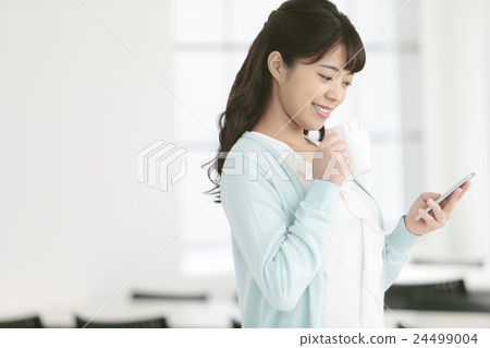 A woman with a smartphone and a coffee cup A woman with a smartphone and a coffee cup 24499004