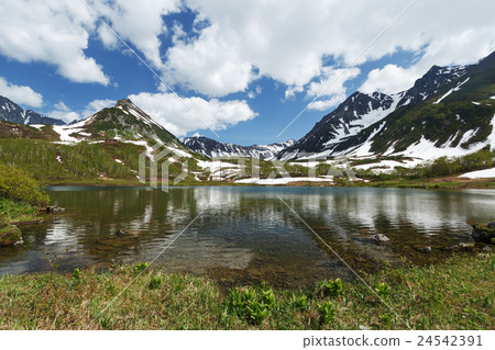 Mountains, mountain lake and clouds in blue sky Mountains, mountain lake and clouds in blue sky 24542391