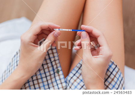 Woman on bed with positive pregnancy test in hands 24563483