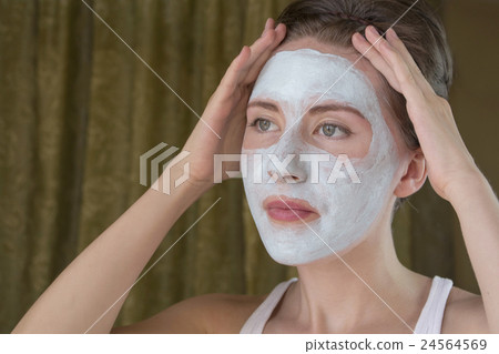 woman doing cosmetic mask on her face 24564569