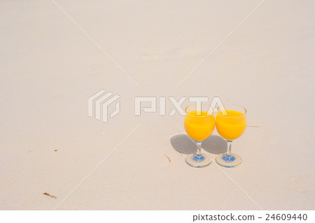 Two glasses of orange juice on tropical white 24609440