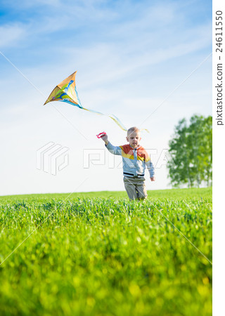 Young boy playing with his kite in a green field.  24611550