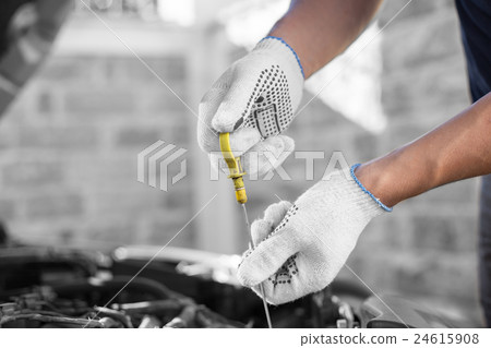 Auto mechanic checking the oil level in car engine 24615908