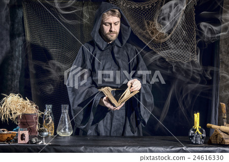 Halloween. The medieval alchemist reading a book  24616330