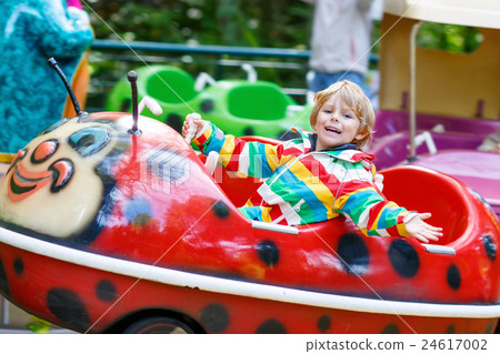 Little kid boy on carousel in amusement park 24617002