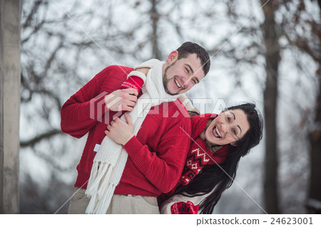 man and woman having fun in the snow-covered park 24623001