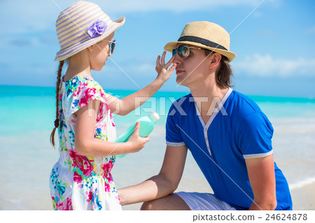 Little girl gets sun cream on her dad's nose Little girl gets sun cream on her dad's nose 24624878