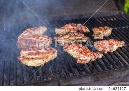 T-bone steak cooking on an open flame grill 24625117