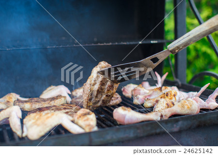 Grilled steak and chiken cooking on an open 24625142