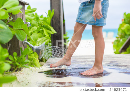 Little cute girl washes out the sand from her feet Little cute girl washes out the sand from her feet 24625471