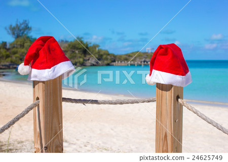 Close-up two Santa hats on fence at tropical white 24625749